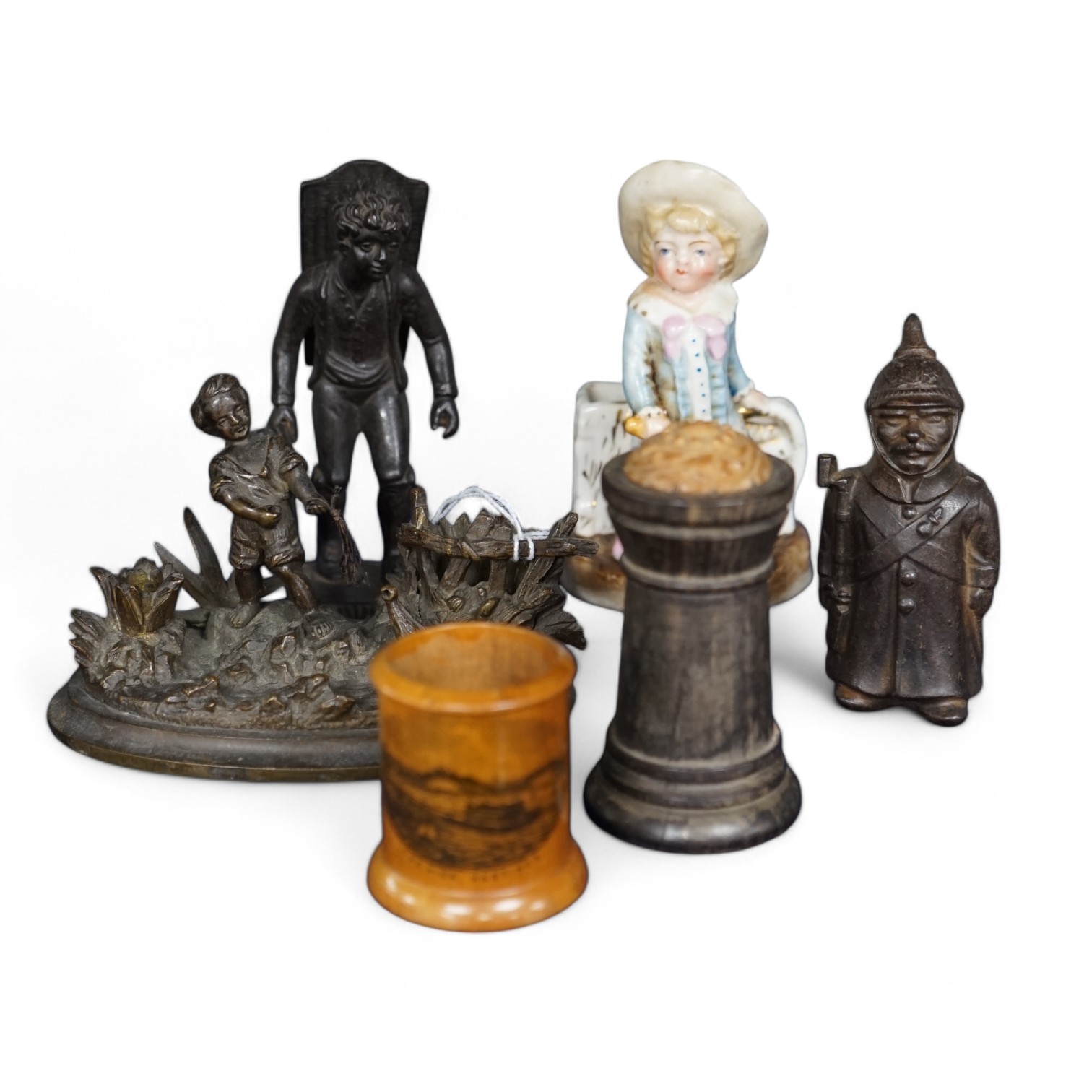 Six match tidies / strikers, including in the form of a WWI German soldier in trench coat and pickelhaube, a Mauchline ware pot with image of Hastings Pier, a cast metal figure of a boy, etc. Condition - fair